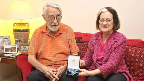 Inocenta Sánchez muestra la Medalla al Mérito Civil acompañada de su marido, John Ewart. / Inocenta Sánchez shows her Civil Merit award, along her husband, John Ewart. (EL CORREO)