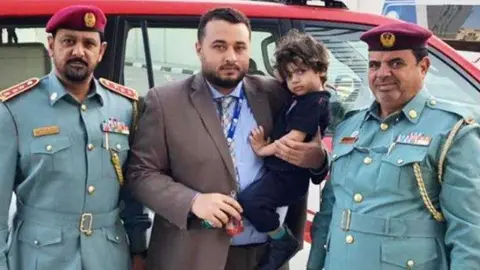 La Policía de Ajman distribuyó esta imagen de los padres con el menor y los agentes que lo encontraron.