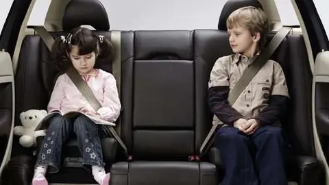 Menores sentados en el asiento trasero de un vehículo.