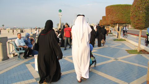 Una pareja de emiratíes camina por la Corniche de Abu Dhabi ataviada con las vestimentas tradicionales de Emiratos Árabes Unidos. (ELCORREO)
