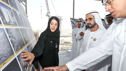 El jeque Mohammed bin Rashid Al Maktoum, vicepresidente y primer ministro de Emiratos Árabes Unidos y gobernante de Dubai -en el centro-, atiende en el recinto de la Expo 2020 las explicaciones de la ministra de Estado de Cooperación Internacional. (WAM)