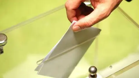 Votante deposita el sobre con la papeleta en una urna. 