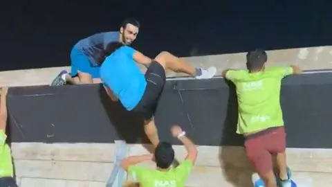 El jeque Hamdan de espaldas escala un muro en una carrera de obstáculos.