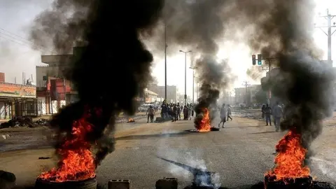 En la imagen de Reuters,  manifestantes sudaneses usan neumáticos quemados para erigir una barricada en una calle.