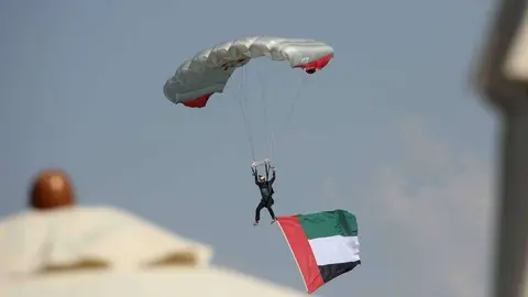 Un paracaidista porta la bandera de Emiratos Árabes en su descenso hacia la Marina de Abu Dhabi. (EL CORREO)