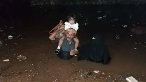Una familia huye de las inundaciones en Adén.
