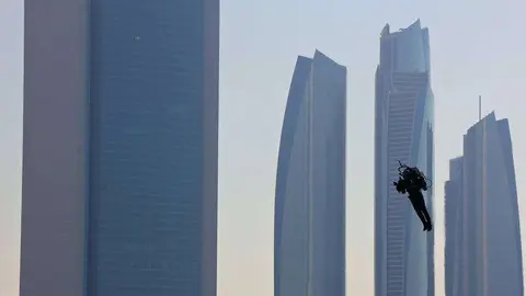 Un hombre volador pasea en Abu Dhabi ante el edificio de ADNOC, situado a la izquierda. (R. Pérez / EL CORREO)
