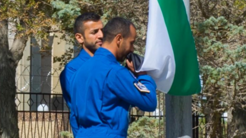 Astronautas emiratíes besan la bandera de su país durante la ceremonia de izado. (WAM)