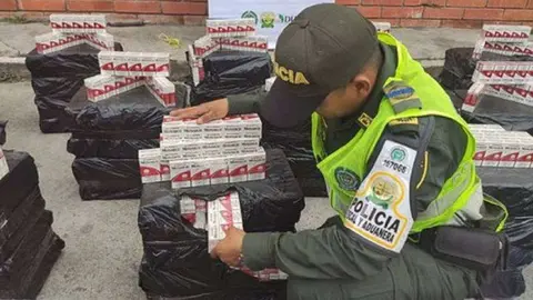 Un oficial colombiano con las cajetillas de tabaco. (Caracol Radio)