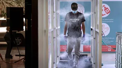 Un trabajador pasa por un túnel de desinfección en Abu Dhabi.