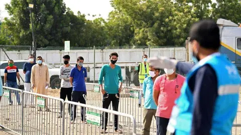 En la imagen de AFP, trabajadores hacen cola para realizarse la prueba de Covid-19.