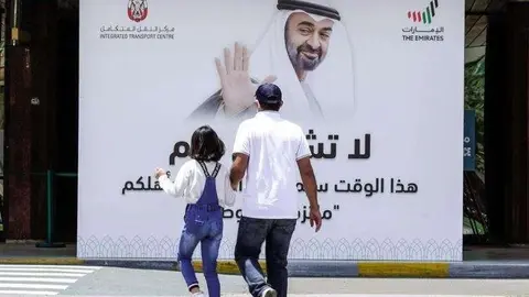 Un padre y su hija caminan por una calle de EAU. (The National)