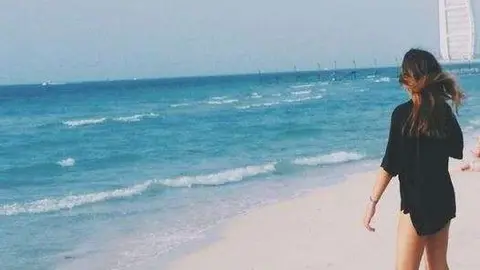 Una joven en una playa de Dubai con el Burj Al Arab al fondo. (EL CORREO)