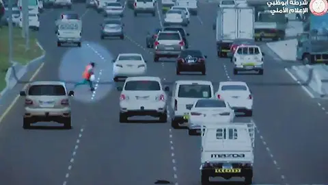 Una captura del vídeo de la Policía de Abu Dhabi muestra al hombre cruzando la calle, causando confusión entre los automovilistas.