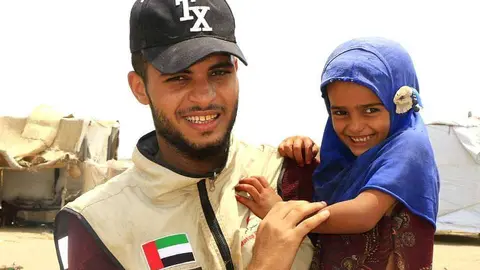 Emiratí con una niña receptora de la ayuda humanitaria que EAU proporciona al pueblo yemení. (WAM)