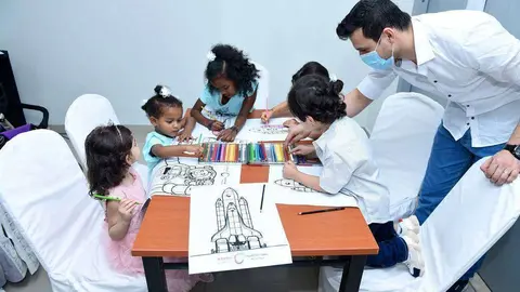 Niños colorean naves espaciales durante la jornada de puertas abiertas en la Ciudad Humanitaria. (WAM)
