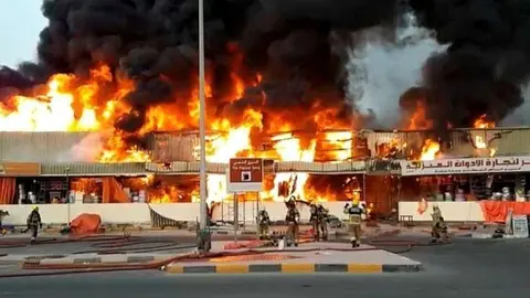 Efectivos de bomberos intervienen en el incendio declarado en la tarde del mi&eacute;rcoles en un zoco de Ajman. (WAM)