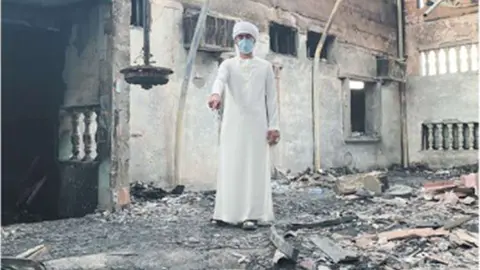 Uno de los hijos muestra la casa donde tuvo lugar el incendio. (Al Khaleej)