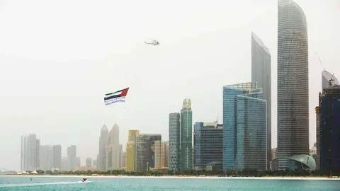 El helicóptero con la bandera de EAU sobrevuela Abu Dhabi. (WAM)
