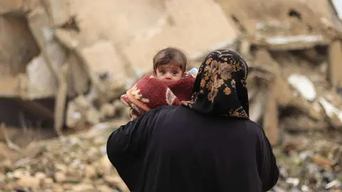 Una madre recorre con su hijo las calles destruidas de Alepo a comienzos del año 2020. (UNICEF / Al-Issa)