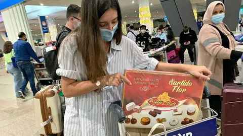 La andaluza Celia Pérez, procedente de Madrid, a su llegada en la medianoche del miércoles a un abarrotado Aeropuerto Internacional de Dubai con una caja de los exquisitos dulces de Navidad de la Flor de Rute. (EL CORREO)
