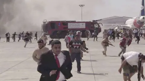 Decenas de personas huyen de la zona donde se localizó el atentado en el aeropuerto de Adén. (Twitter)