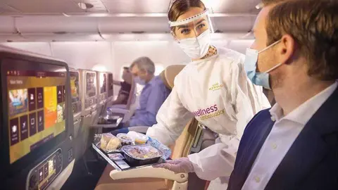 Una asistente de vuelo atiende a un pasajero en un vuelo de Etihad.