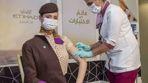 Una tripulante de cabina recibe una dosis de la vacuna Covid. (WAM)