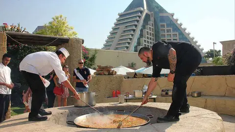El chef del Seville's, Aleix Font -derecha-, prepara a leña en la terraza del restaurante una auténtica paella valenciana a leña. (EL CORREO)