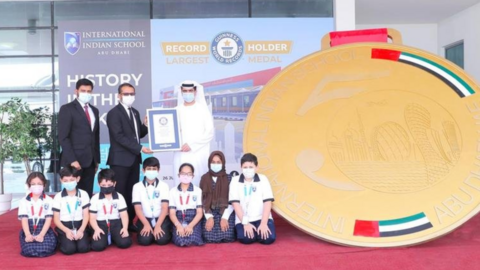 Estudiantes y profesores posan con la medalla de oro más grande del mundo. (Twitter)