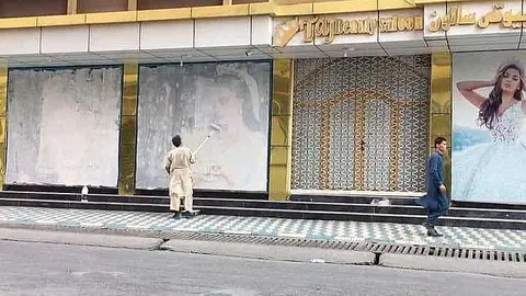 Foto que circula en las redes sociales este domingo sobre Kabul en la que una persona elimina imágenes de mujeres. 