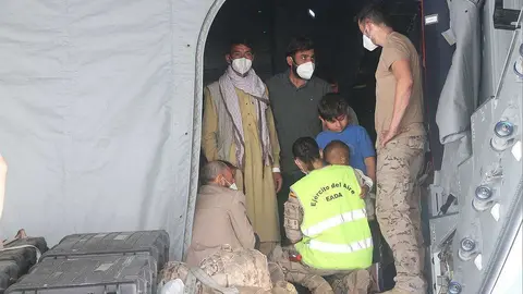 Militares españoles atienden a afganos evacuados a su llegada a Dubai procedentes de Kabul. (R. Pérez / EL CORREO)