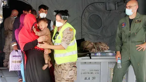 Militar española ayuda a una afgana y su hijo a descender del avión en la Base Aérea de Al Minhad en Dubai. (R. Pérez / EL CORREO)