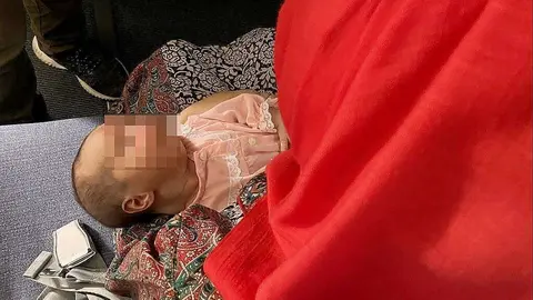 Niña afgana de 25 días en brazos de su madre en el avión en que fue trasladada desde Dubai a Madrid por España. (EL CORREO)