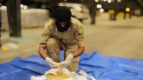 Un funcionario saudí muestra parte del alijo de pastillas de anfetamina. (SPA)