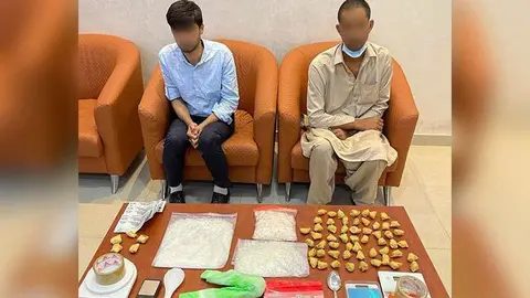 Dos de los sospechosos junto a las drogas confiscadas. (Policía de RAK)