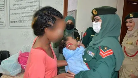 Un miembro de la Policía de Dubai entrega a una madre su bebé. (Policía de Dubai)