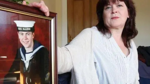 La madre muestra una imagen del marinero desaparecido. (Fuente externa)