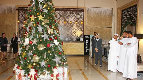 Varios árabes observan el árbol de Navidad en el hotel Occidental Al Jaddaf. (EL CORREO)