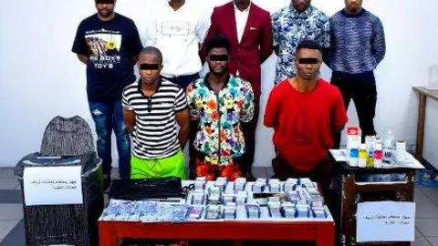 La banda detenida junto a los utensilios usados para falsificar los billetes. (Policía de Sharjah)