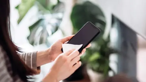 Una mujer limpia su teléfono móvil. (WAM)