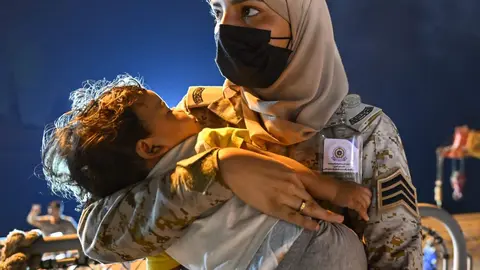 Un niño se queda dormido en brazos de una empleada del Ministerio de Defensa saudí. (Instagram pplofsaudia)