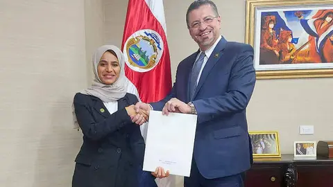 El presidente de Costa Rica recibe la invitación de manos de la embajadora emiratí Rawdha Alotaiba. (WAM)