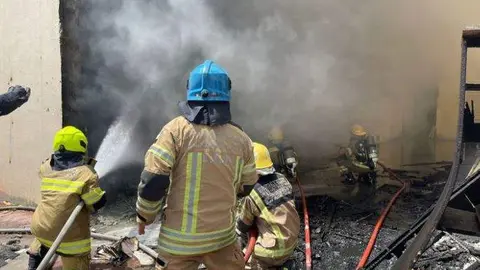 Bombero apagan el fuego en la fábrica textil. (Twitter)