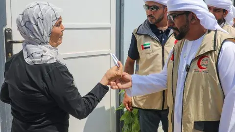 Un funcionario emiratí entrega la llave de una vivienda a una mujer siria. (WAM)