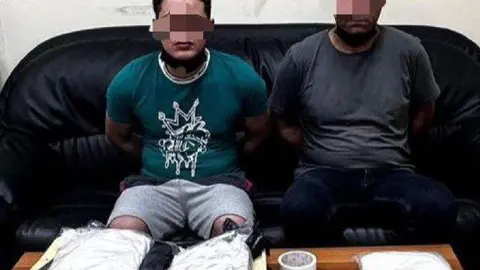 Los detenidos junto a la droga confiscada. (Policía de Abu Dhabi)