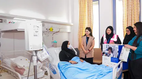 Una madre junto a su bebé reciben la sillita de coche. (RTA)