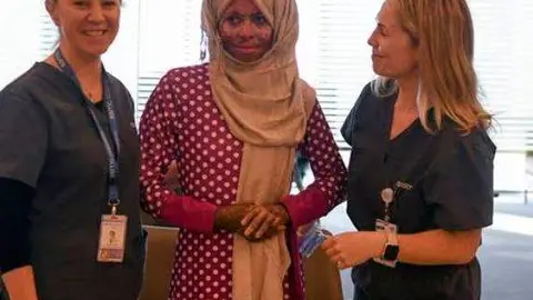 En el centro de la imagen la trabajadora tras el alta hospitalaria. (The National)