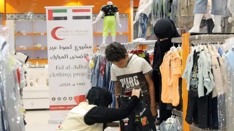 Una trabajadora de Emiratos prueba un pantalón a un niño en Yemen. (WAM)