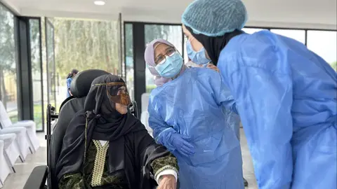 Una anciana en Sharjah con sus cuidadoras. (WAM)